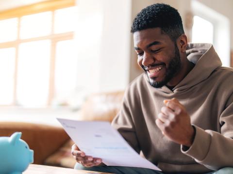 Male student holding a piece of paper and smiling