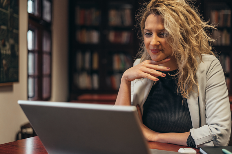 Woman looking at a laptop screen in a library.